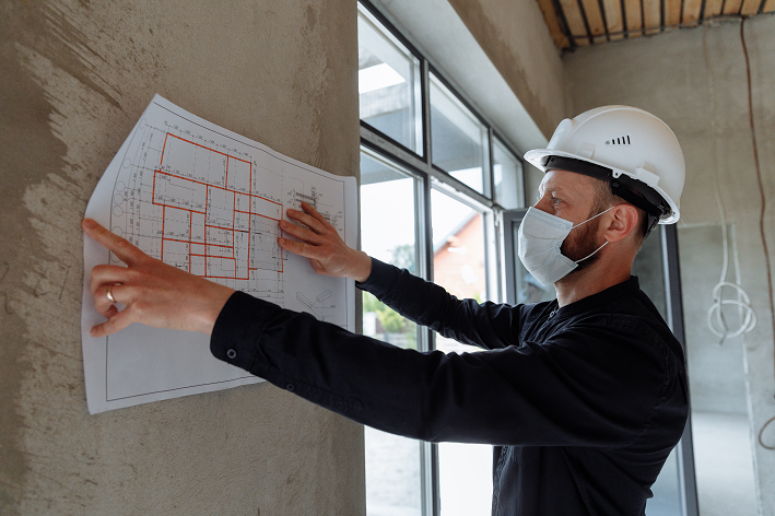 Engenheiro de obra analisa a planta de uma construção.