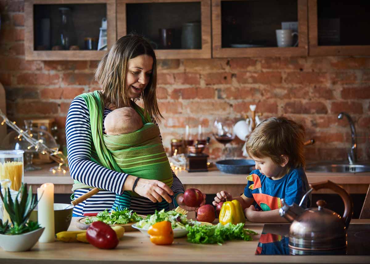 Família jovem, mãe com duas crianças cozinhando juntas, alimentação saudável