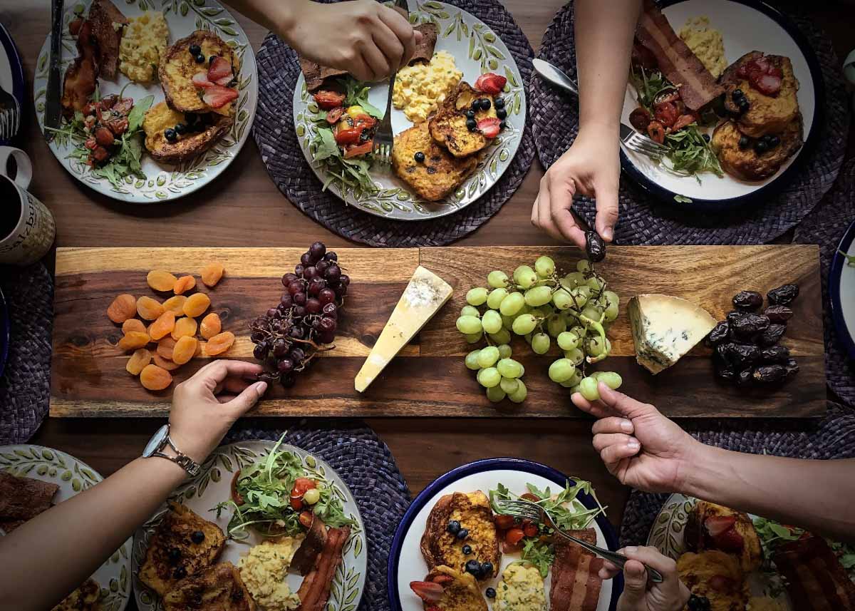 Mesa com diversos pratos, frutas e queijos exemplificando uma refeição gastronômica