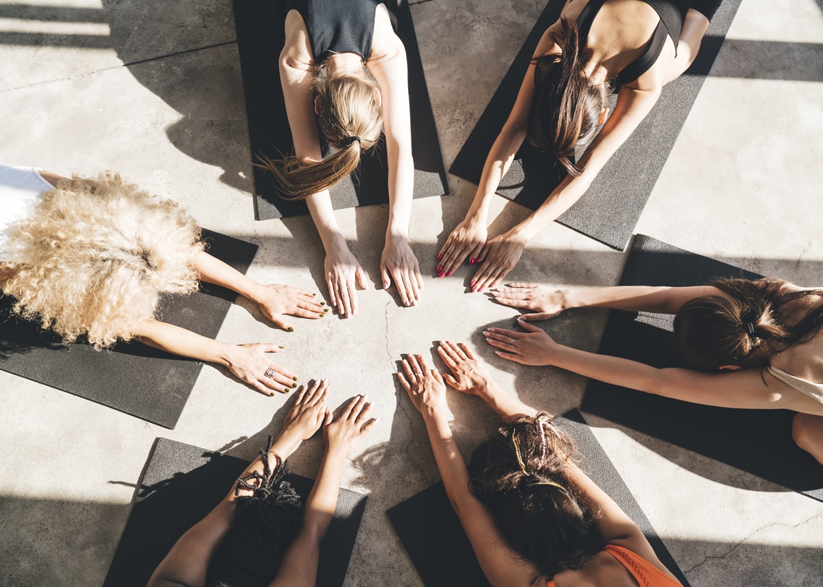 Vista superior de mulheres sentadas em esteiras em círculo praticando yogaterapia